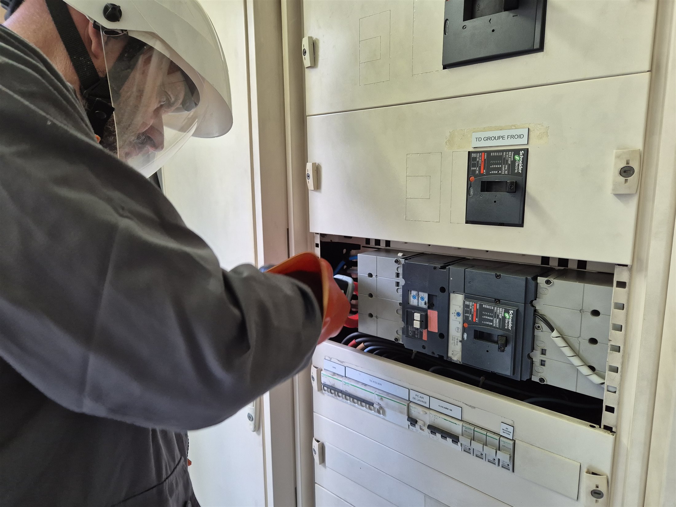 Technicien réalisant des mesures sur un tableau électrique
