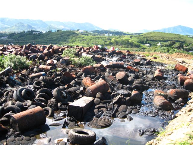 Zone de déchets dégradée avec fûts, pneus et sols pollués
